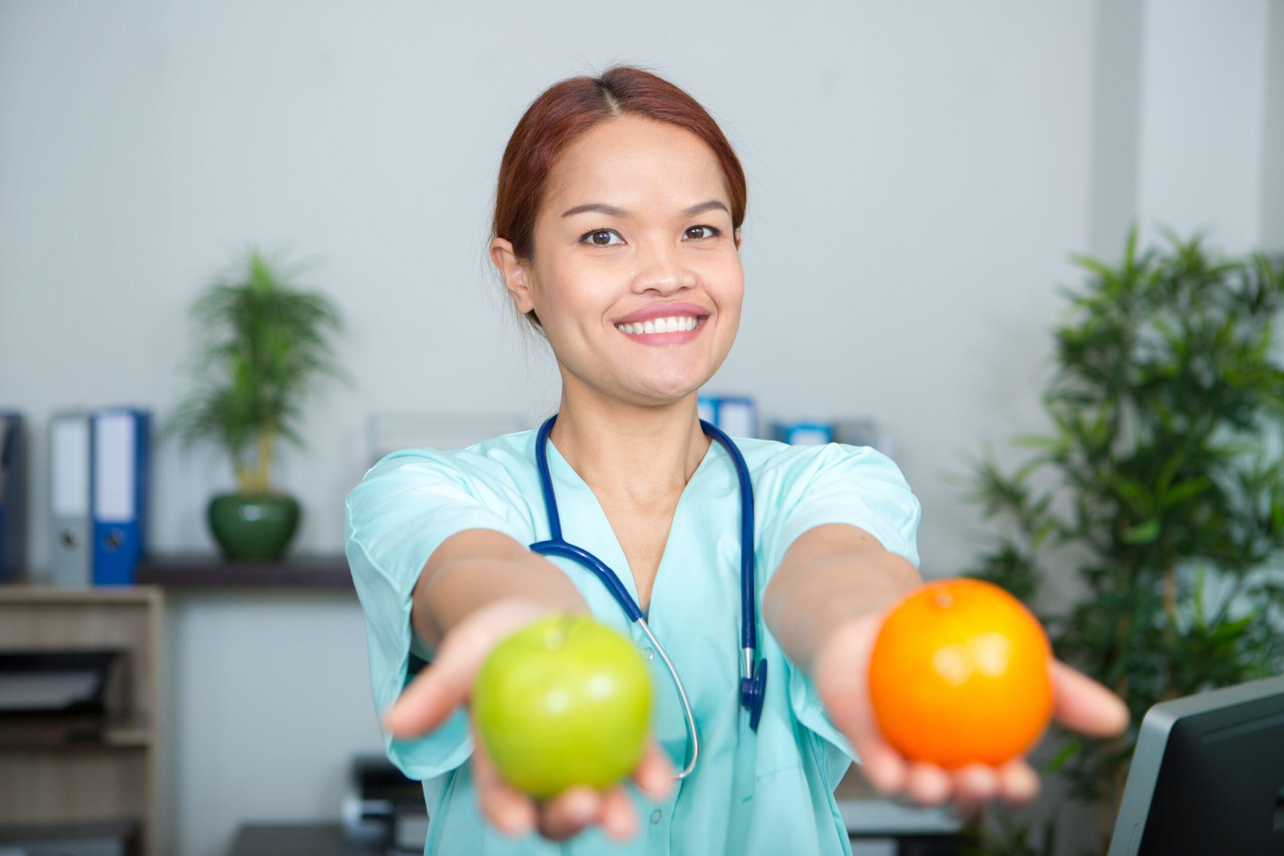 a female doctor holding apple and orange