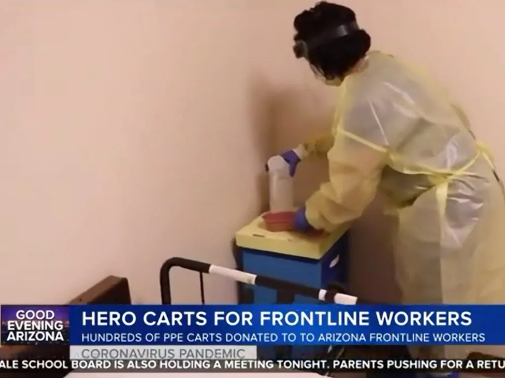 Healthcare worker in yellow gown and purple gloves organizing PPE carts for frontline workers during coronavirus pandemic